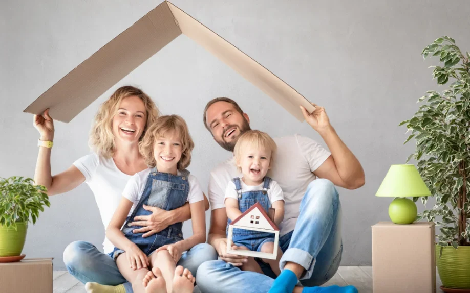 Familie mit zwei Kindern unter einem symbolischen Hausdach